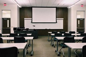 empty classroom with white desks and black chairs