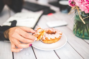 woman's hand holding a piece of doughnut