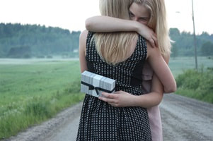 two girls hugging with one holding a gift
