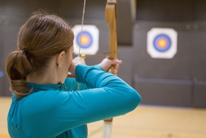 woman aiming a bow and arrow at target