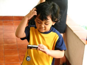 little boy scratching his head looking at digital camera screen