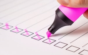 fingers using a pink highlighter to check boxes on a list