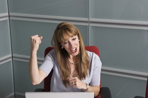 excited woman looking at computer screen