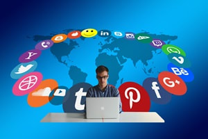man behind laptop with social icons circled around him