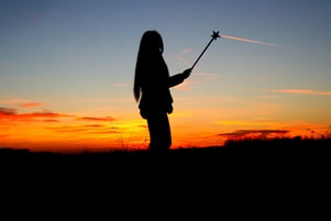 young girl holding a wand against a sunset