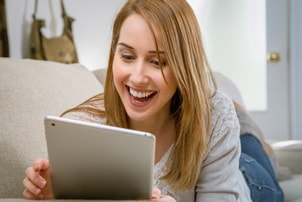 woman smiling while looking at tablet